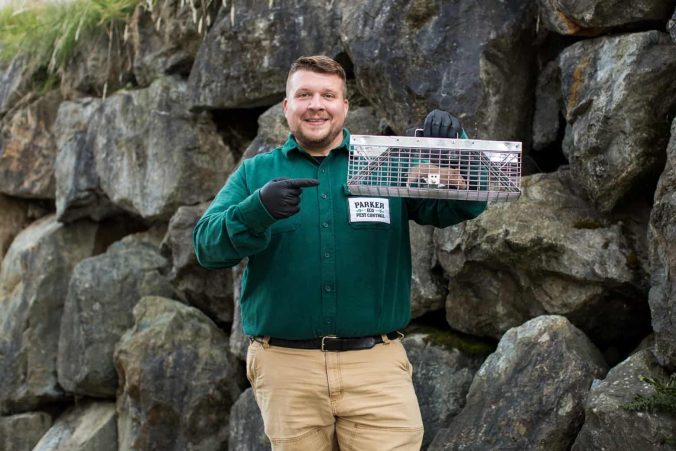 Chris holding up a rodent in cage